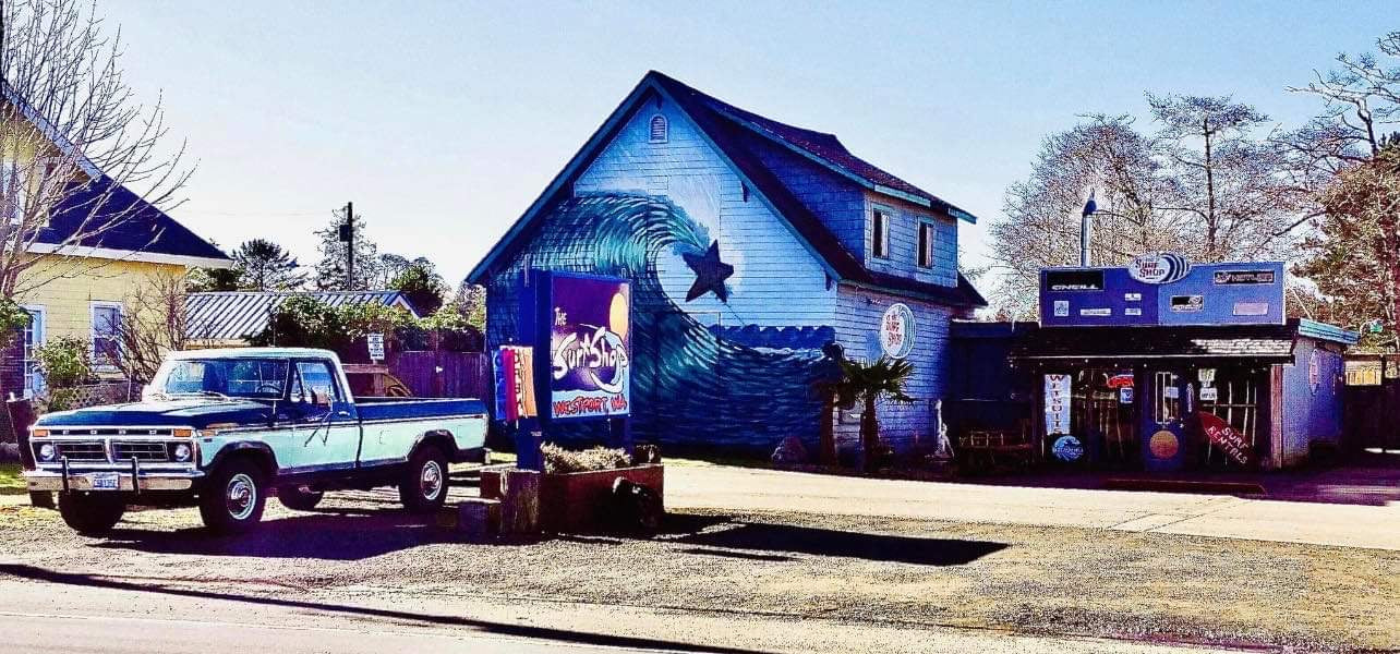 Image of The Surf Shop Westport, WA - A big blue house with a curling wave painted on the side as a classic pickup truck sits out front. 